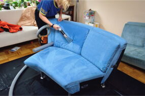 Eine Mitarbeiterin der Teppichreinigung & Polsterreinigung Berlin Karsten Vorwerk bei der Reingung einer blauen Designercouch beim Kunden vor Ort.