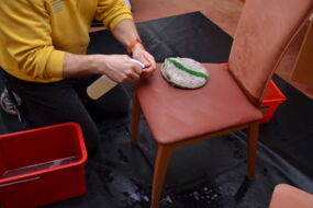 Hier beabeitet unser Mitarbeiter Flecken mit einem speziellen Mittel. Deutlich sieht man den dunklen (nassen) Bereich. Hier wurde bereits mit der Hand schamponniert.
